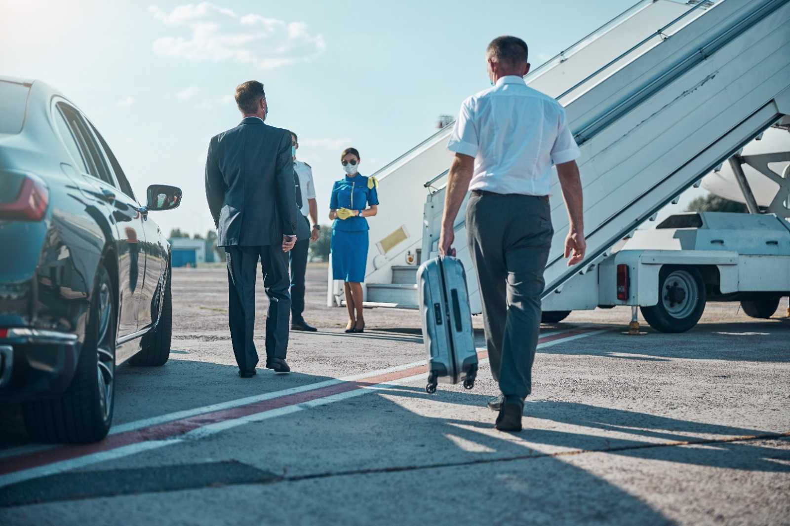 Travelers boarding a flight with a luxury car nearby, representing easy airport transfers with chauffeur service in Dubai.