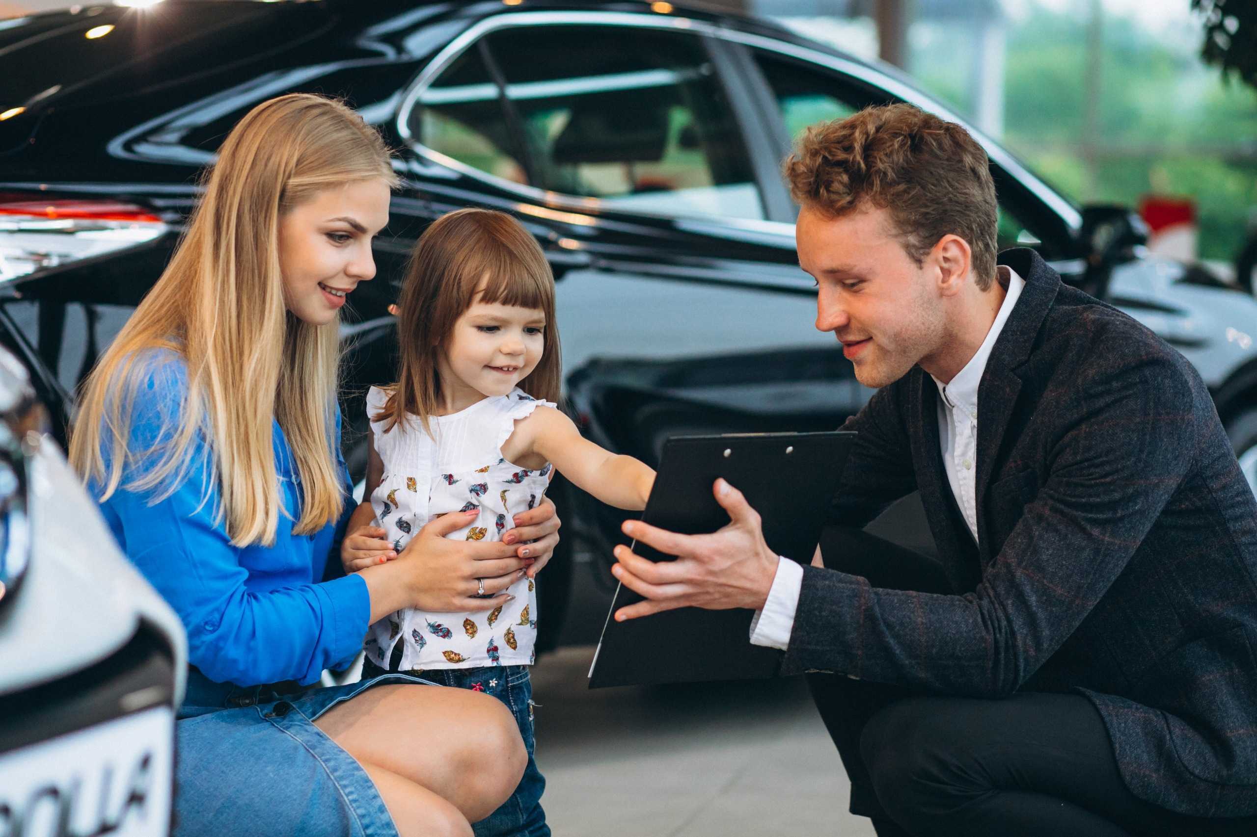 Mother and child consulting with chauffeur service representative at luxury car showroom